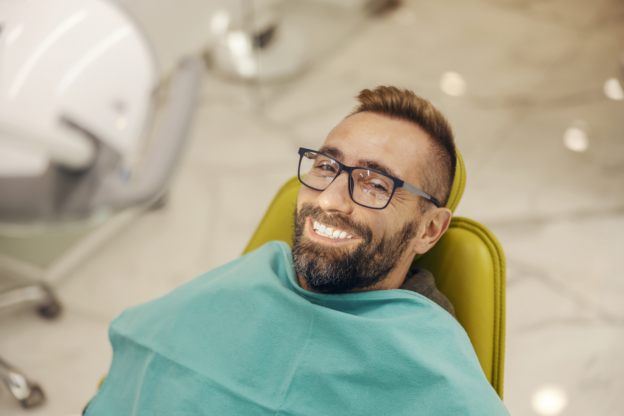 male periodontal patient sitting in dental chair smiling